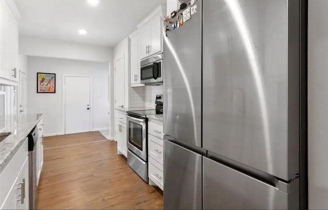 4217 Winfield Ave, Fort Worth, TX 76109 - kitchen featuring appliances with stainless steel finishes, white cabinetry, recessed lighting, light wood-style floors, and light stone counters