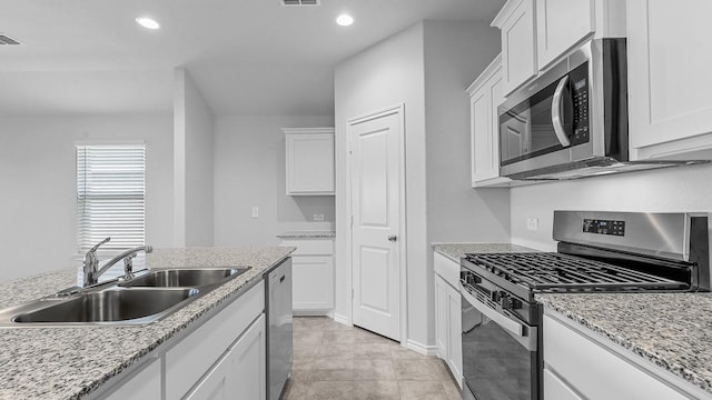 kitchen featuring sink, white cabinets, light tile patterned floors, light stone counters, and stainless steel appliances