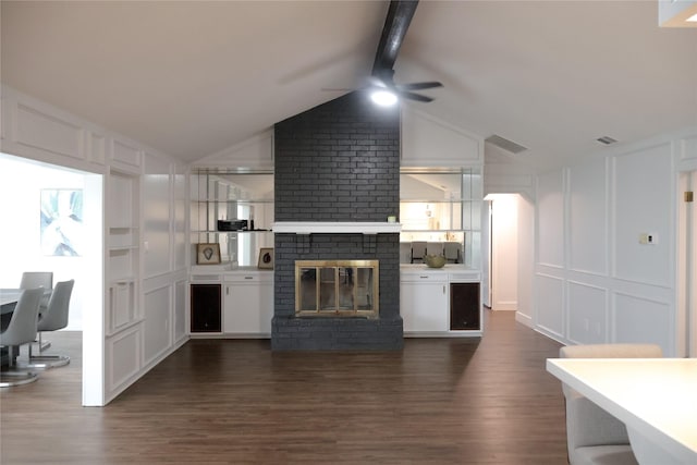 kitchen featuring vaulted ceiling with beams, dark wood-type flooring, a fireplace, and ceiling fan