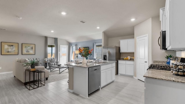 kitchen featuring sink, white cabinetry, stainless steel appliances, light stone countertops, and a kitchen island with sink