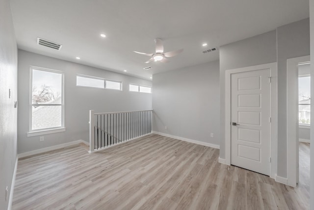 spare room featuring ceiling fan, a healthy amount of sunlight, and light wood-type flooring