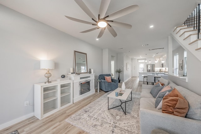 living room with light hardwood / wood-style floors and ceiling fan