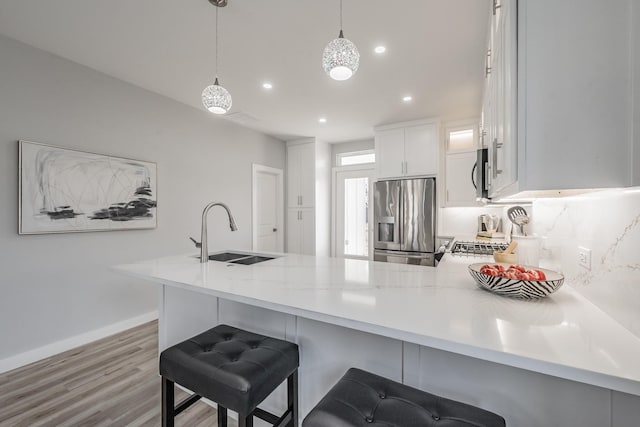 kitchen featuring a breakfast bar, decorative light fixtures, white cabinets, kitchen peninsula, and stainless steel appliances