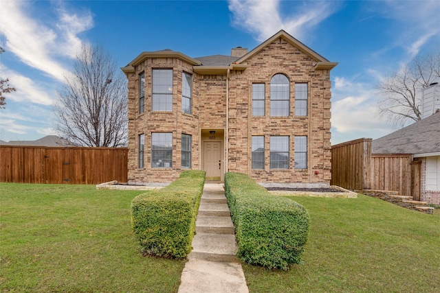 traditional-style home featuring brick siding, a front lawn, a chimney, and fence