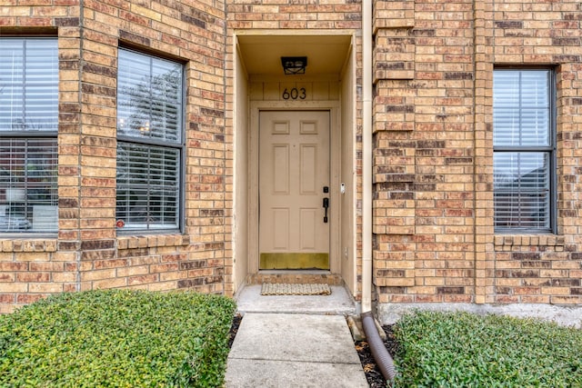 view of exterior entry featuring brick siding