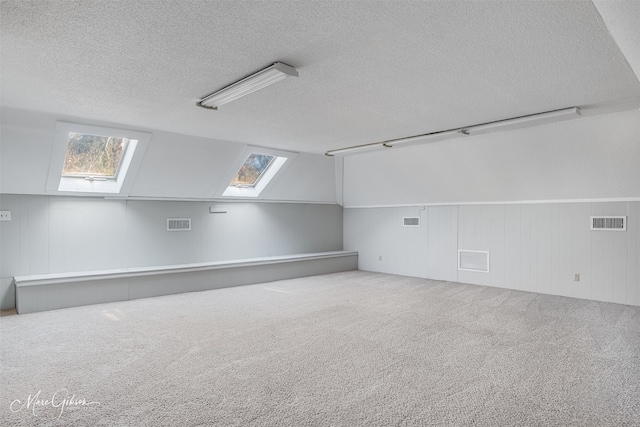 bonus room featuring carpet flooring, a textured ceiling, and lofted ceiling with skylight