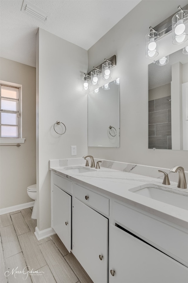 bathroom featuring vanity, a textured ceiling, and toilet