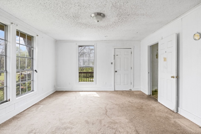 carpeted spare room with baseboards, a textured ceiling, and crown molding