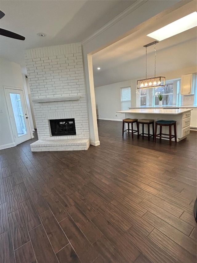 unfurnished living room with a brick fireplace, a wealth of natural light, dark hardwood / wood-style floors, and ceiling fan