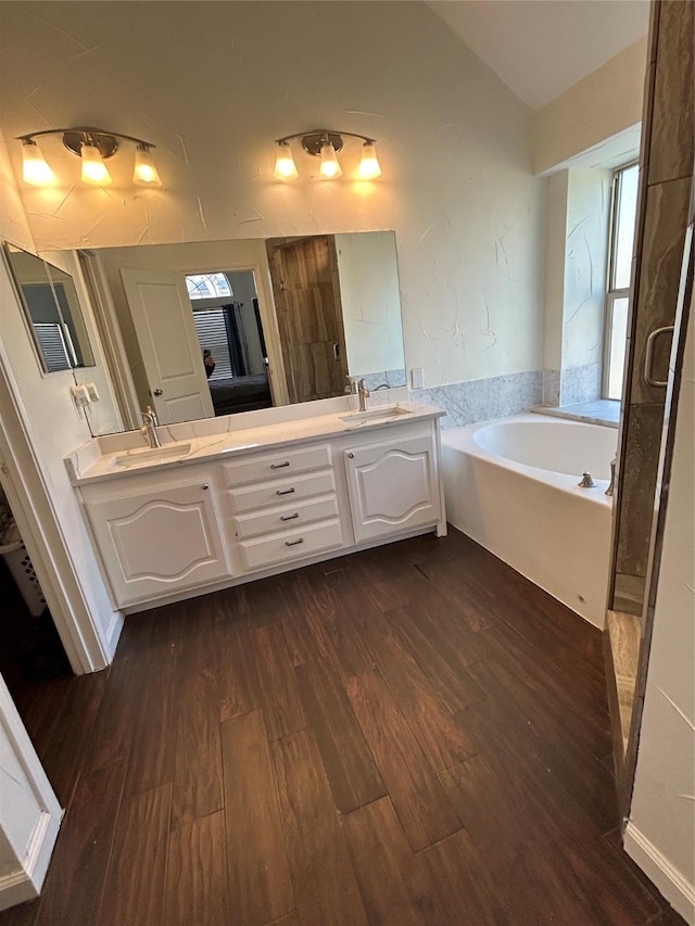 bathroom featuring vanity, hardwood / wood-style floors, lofted ceiling, and a bathing tub