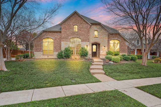 french country inspired facade featuring a lawn