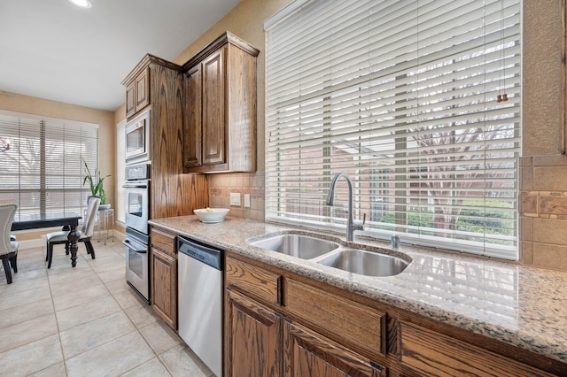 kitchen featuring light stone counters, sink, light tile patterned floors, and stainless steel appliances