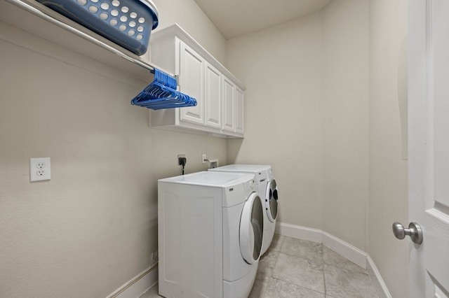 laundry area with cabinets, washer and dryer, and light tile patterned floors