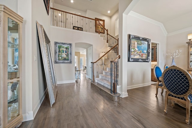 entryway with crown molding, dark wood-type flooring, and high vaulted ceiling