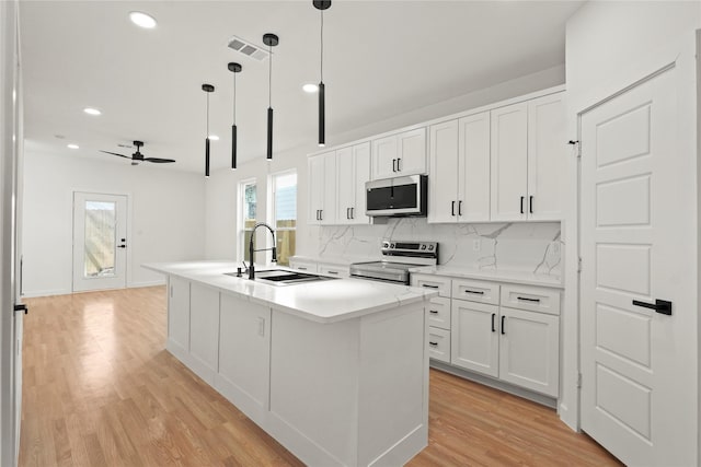 kitchen with visible vents, a sink, decorative backsplash, light wood-style floors, and appliances with stainless steel finishes