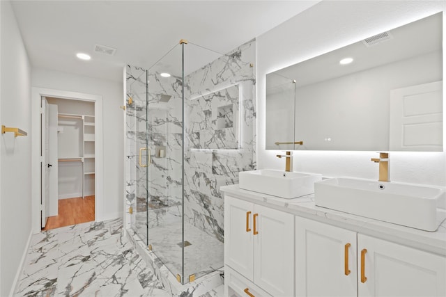 full bath with marble finish floor, visible vents, a sink, and a marble finish shower