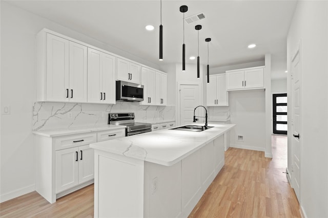 kitchen featuring stainless steel appliances, a sink, visible vents, and white cabinets