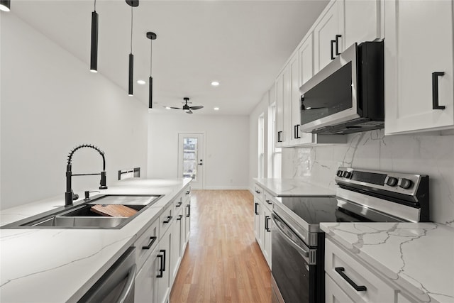 kitchen featuring white cabinets, decorative backsplash, stainless steel appliances, and a sink