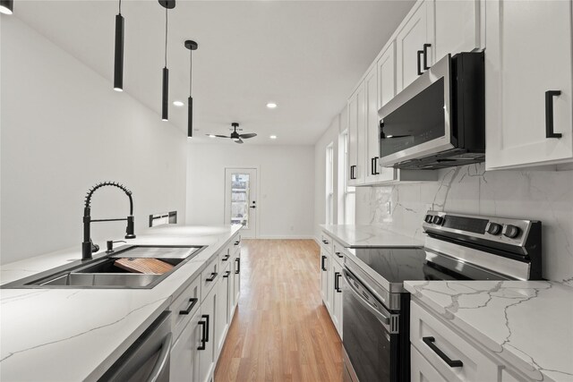 kitchen featuring a sink, light wood-style floors, light countertops, appliances with stainless steel finishes, and tasteful backsplash