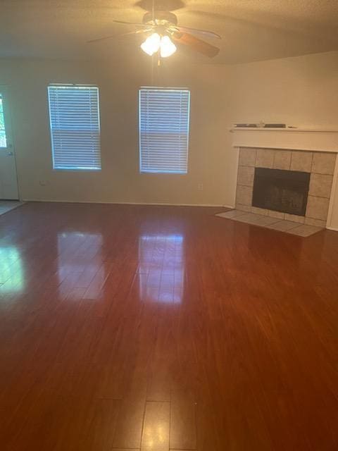 unfurnished living room with a tile fireplace, hardwood / wood-style floors, a textured ceiling, and ceiling fan