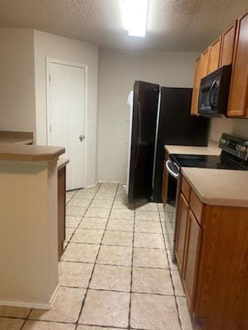 kitchen featuring light tile patterned floors, stainless steel range with electric cooktop, and a textured ceiling