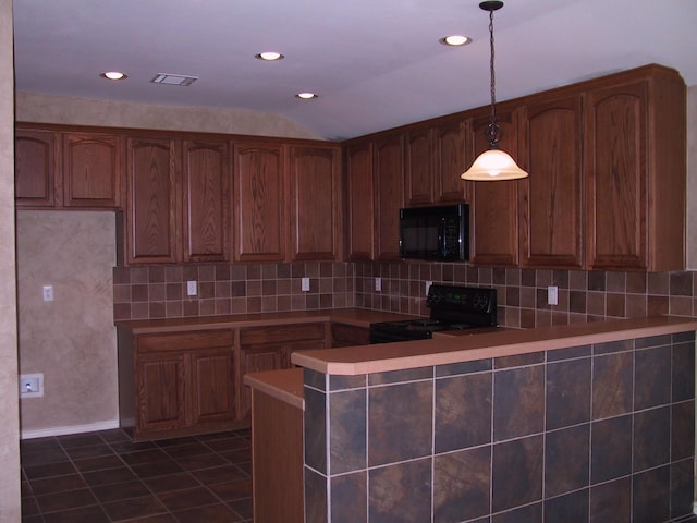 kitchen featuring decorative light fixtures, kitchen peninsula, dark tile patterned floors, decorative backsplash, and black appliances