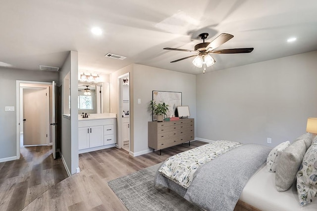 bedroom with ceiling fan, ensuite bathroom, sink, and light wood-type flooring