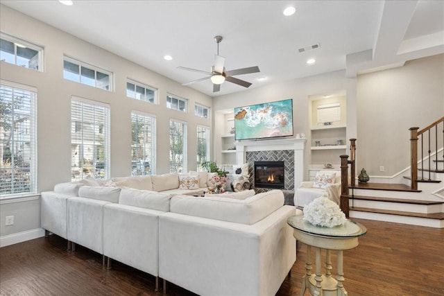 living room featuring ceiling fan, a fireplace, dark hardwood / wood-style flooring, and built in shelves