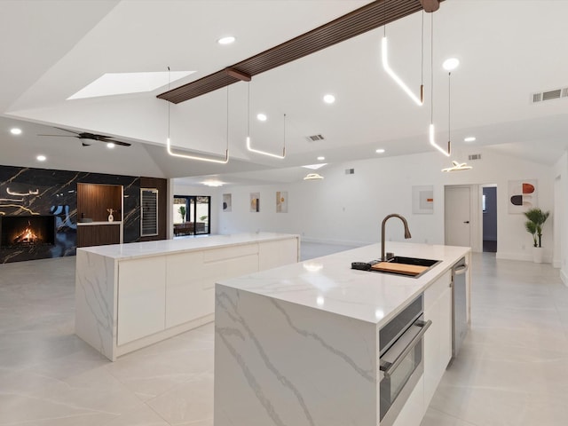 kitchen featuring a large island with sink, pendant lighting, white cabinets, and stainless steel appliances