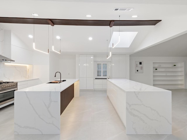 kitchen with sink, white cabinets, hanging light fixtures, a large island, and gas range