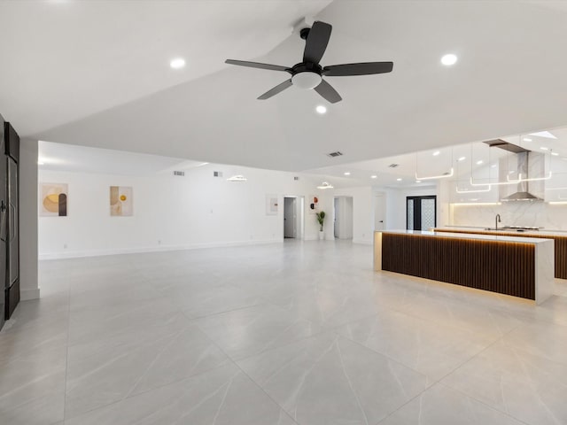 unfurnished living room with ceiling fan, sink, and vaulted ceiling