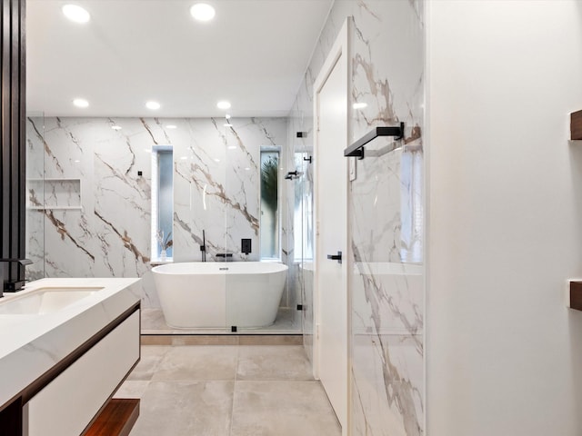 bathroom with vanity, a washtub, and tile walls