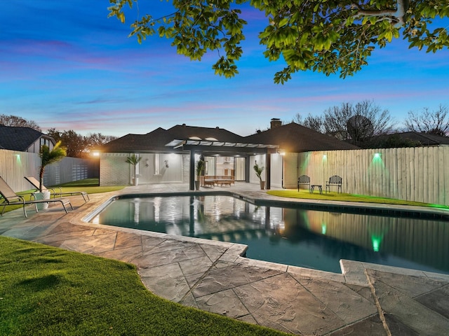 pool at dusk featuring a patio, a yard, and a pergola