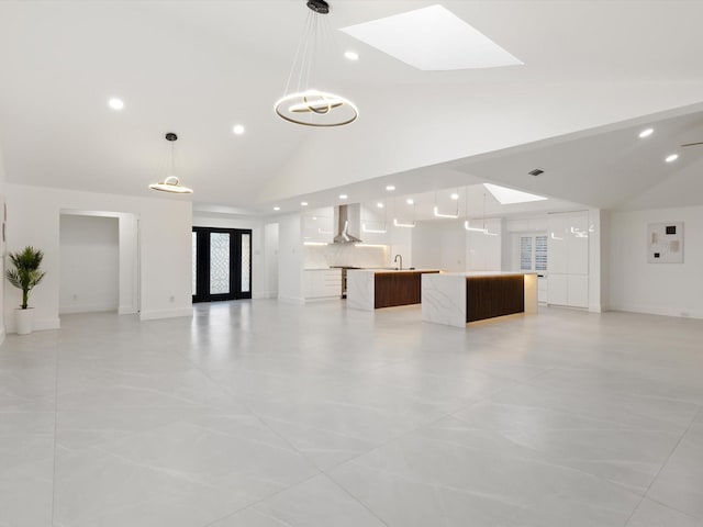 unfurnished living room featuring french doors, sink, high vaulted ceiling, and a skylight