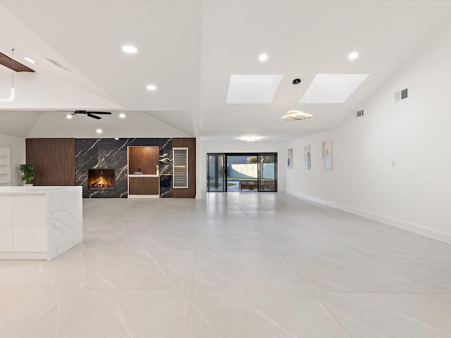 interior space with a skylight, a premium fireplace, and ceiling fan