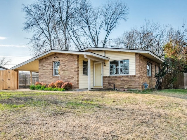 view of front of home with an attached carport, brick siding, fence, and a front lawn