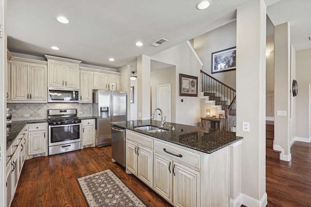 kitchen featuring dark hardwood / wood-style floors, sink, dark stone counters, stainless steel appliances, and cream cabinetry