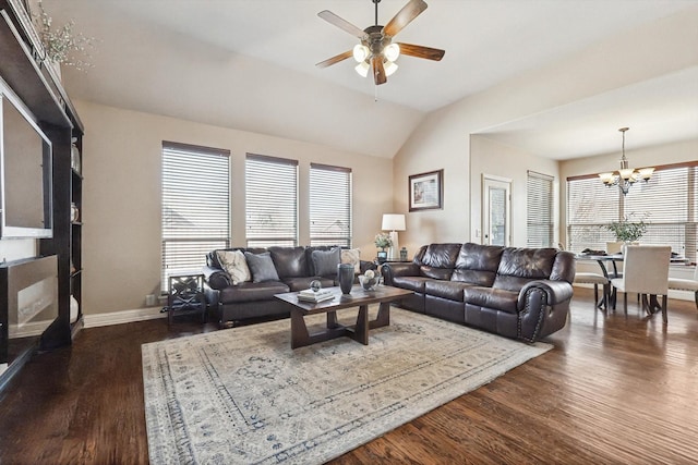 living room featuring ceiling fan with notable chandelier, a healthy amount of sunlight, dark hardwood / wood-style flooring, and vaulted ceiling