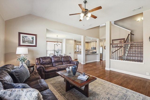 living room with dark hardwood / wood-style flooring, ceiling fan with notable chandelier, and vaulted ceiling