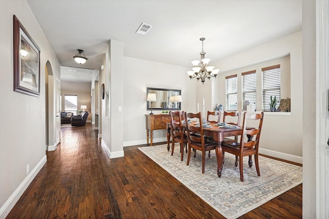 dining area with dark wood-type flooring and a chandelier