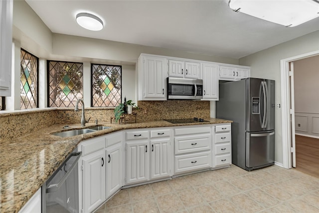 kitchen with stainless steel appliances, white cabinetry, light stone countertops, and sink