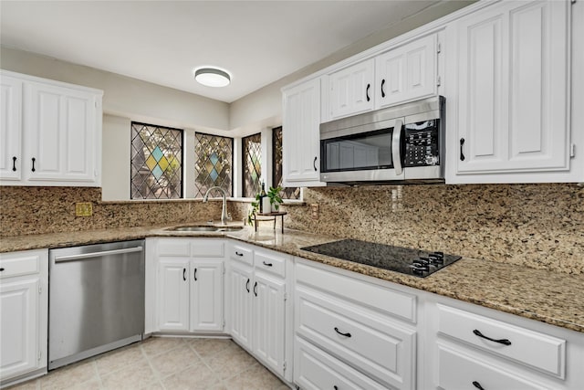 kitchen with appliances with stainless steel finishes, stone countertops, sink, and white cabinets