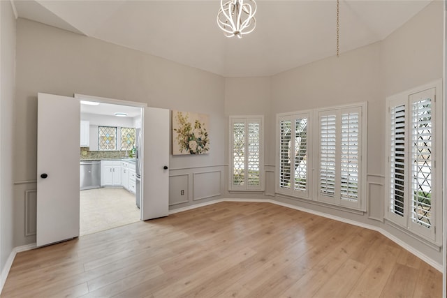 spare room featuring a notable chandelier and light wood-type flooring