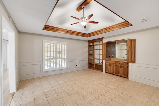 empty room featuring a raised ceiling, sink, and ceiling fan