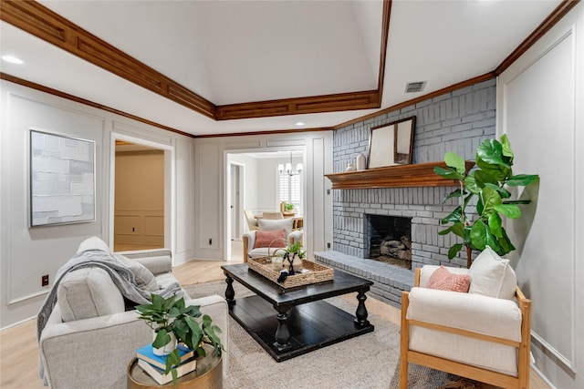 living room featuring crown molding, a fireplace, and light hardwood / wood-style flooring