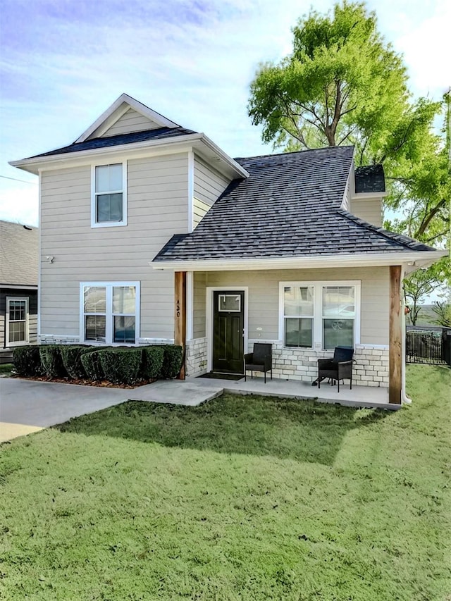 rear view of house with stone siding, a lawn, a patio, and fence