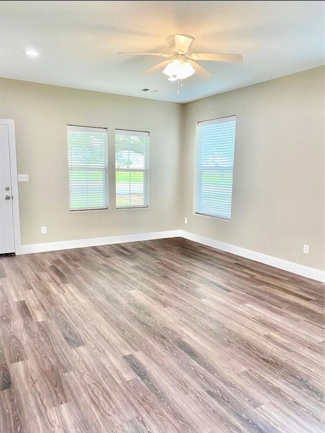 unfurnished room featuring a ceiling fan, visible vents, baseboards, and wood finished floors