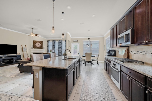 kitchen featuring sink, light stone counters, a center island with sink, appliances with stainless steel finishes, and pendant lighting