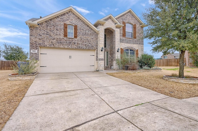 view of front of home featuring driveway, brick siding, stone siding, and fence