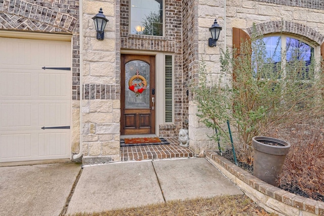 property entrance with stone siding, brick siding, and an attached garage